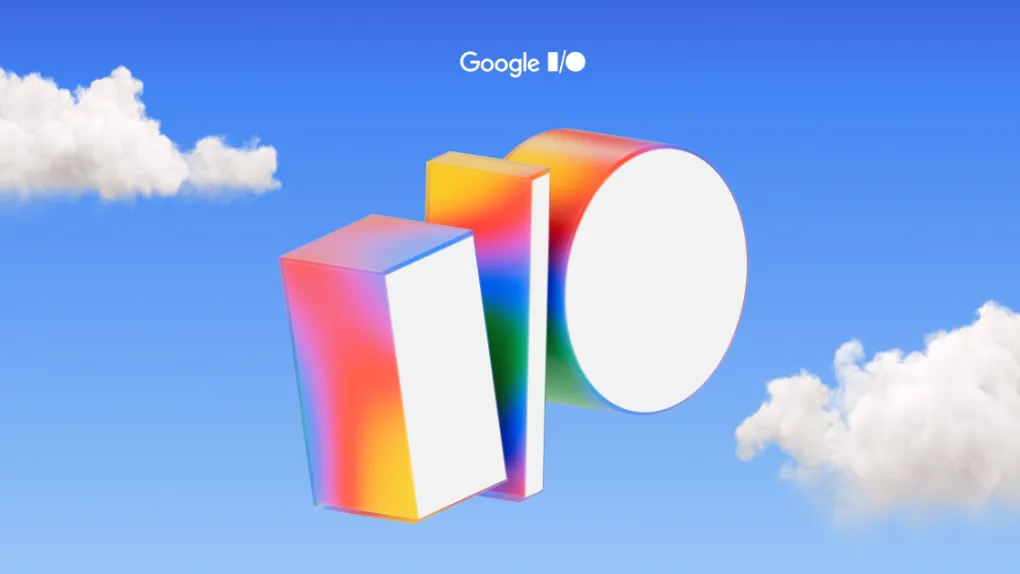 Colorful 3D shapes representing the Google I/O logo floating in a blue sky with clouds, promoting the Google I/O developer conference